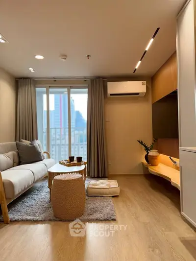 Modern living room with cozy decor, wooden flooring, and balcony view in a stylish apartment.