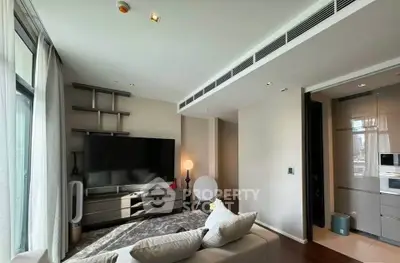 Modern living room with sleek design and large TV, adjacent to a stylish kitchen area.