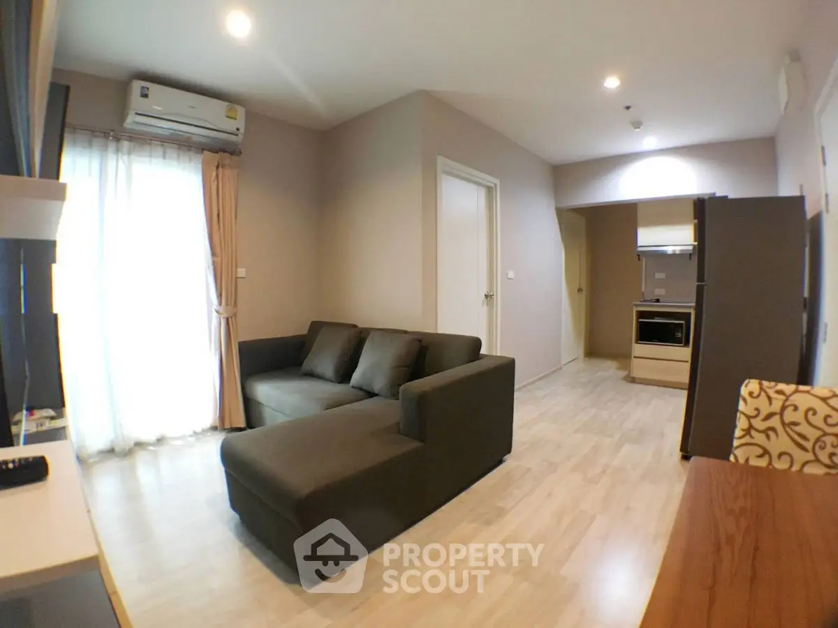 Modern living room with cozy sofa and open kitchen layout in stylish apartment.