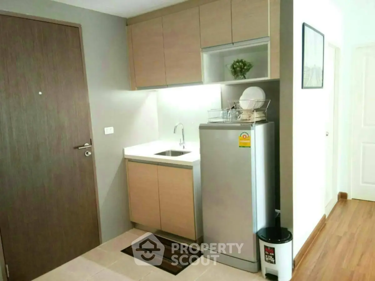 Modern compact kitchen with sleek cabinetry and stainless steel fridge