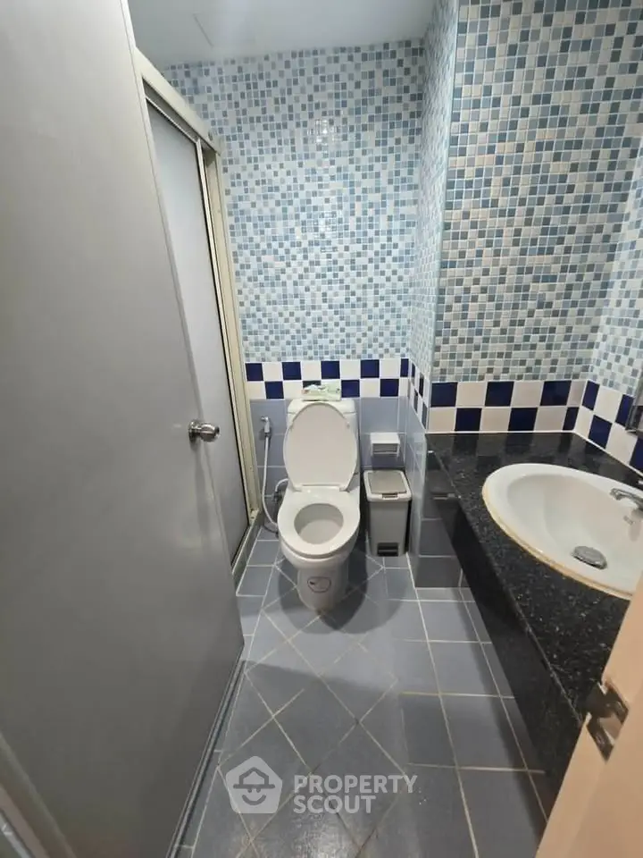 Modern bathroom with mosaic tiles and sleek fixtures in a stylish real estate property.