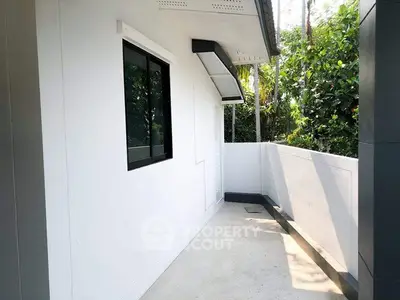 Modern exterior balcony with white walls and lush greenery view