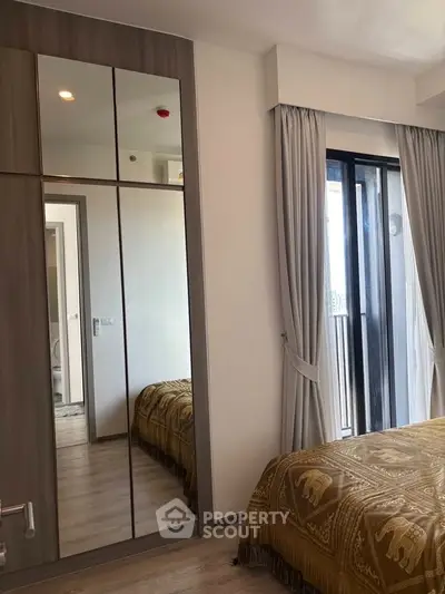 Modern bedroom with mirrored wardrobe and balcony access in stylish apartment.