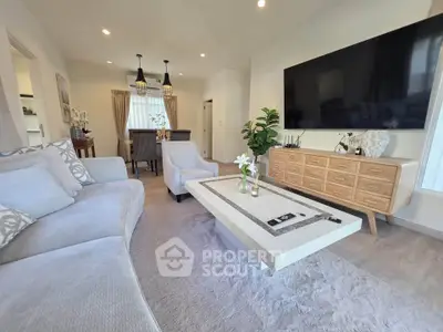 Spacious modern living room with elegant decor and large TV, perfect for relaxation and entertainment.
