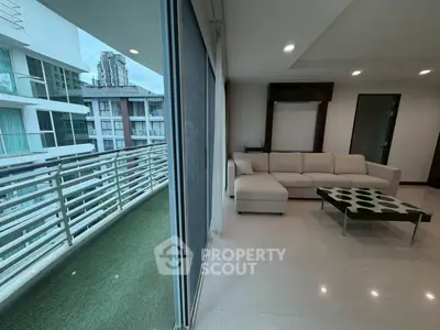 Spacious living room with modern sofa and large balcony offering city views in a luxury apartment.