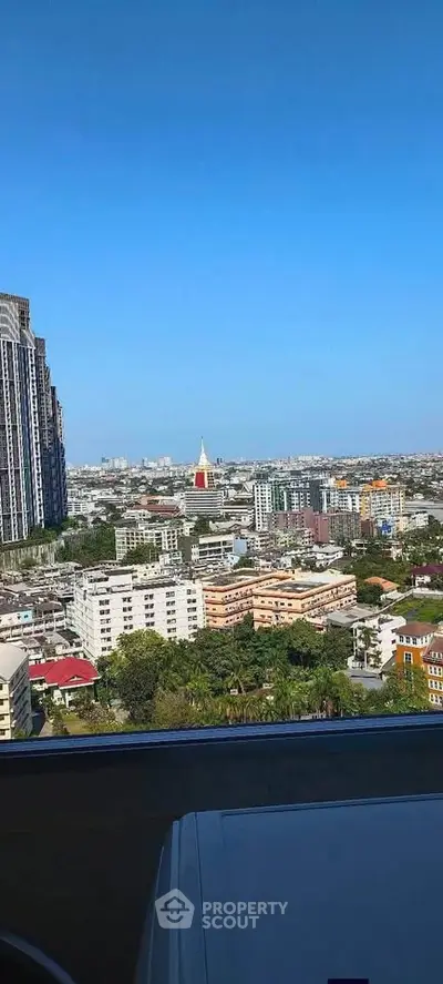 Stunning cityscape view from high-rise apartment balcony with clear blue skies.