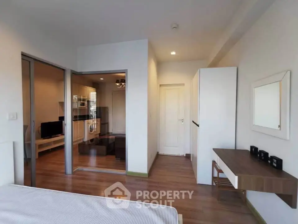 Modern bedroom with wooden flooring and sliding glass doors leading to a cozy living area.
