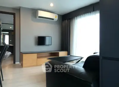 Modern living room with sleek furniture and natural light, featuring a wall-mounted TV and air conditioning.