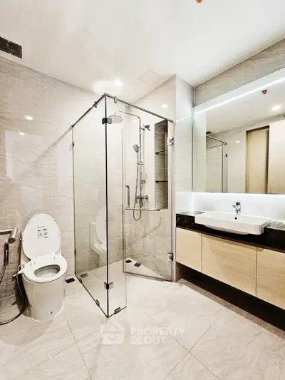 Modern bathroom with glass shower and sleek fixtures in luxury apartment.