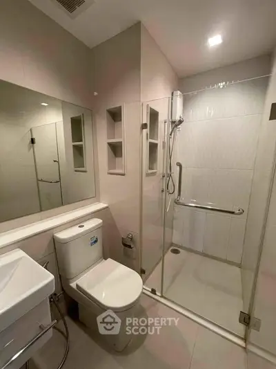 Modern bathroom with glass shower enclosure and sleek fixtures in a contemporary apartment.