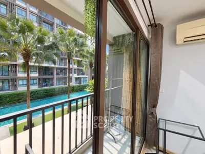 Charming balcony view overlooking lush garden and pool in modern apartment complex.