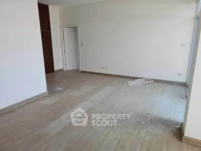 Spacious empty room with wooden flooring and white walls, ready for customization.