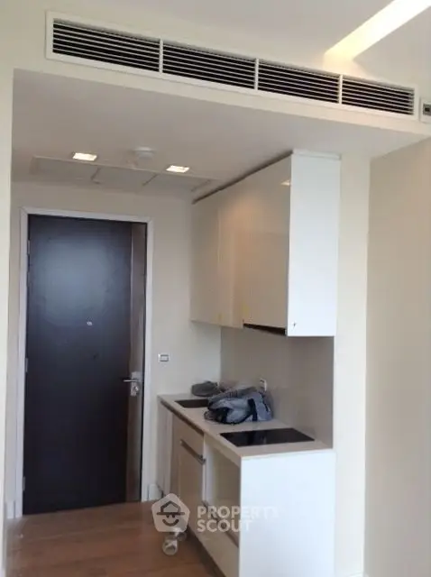 Modern compact kitchen with sleek cabinetry and built-in appliances in a contemporary apartment.