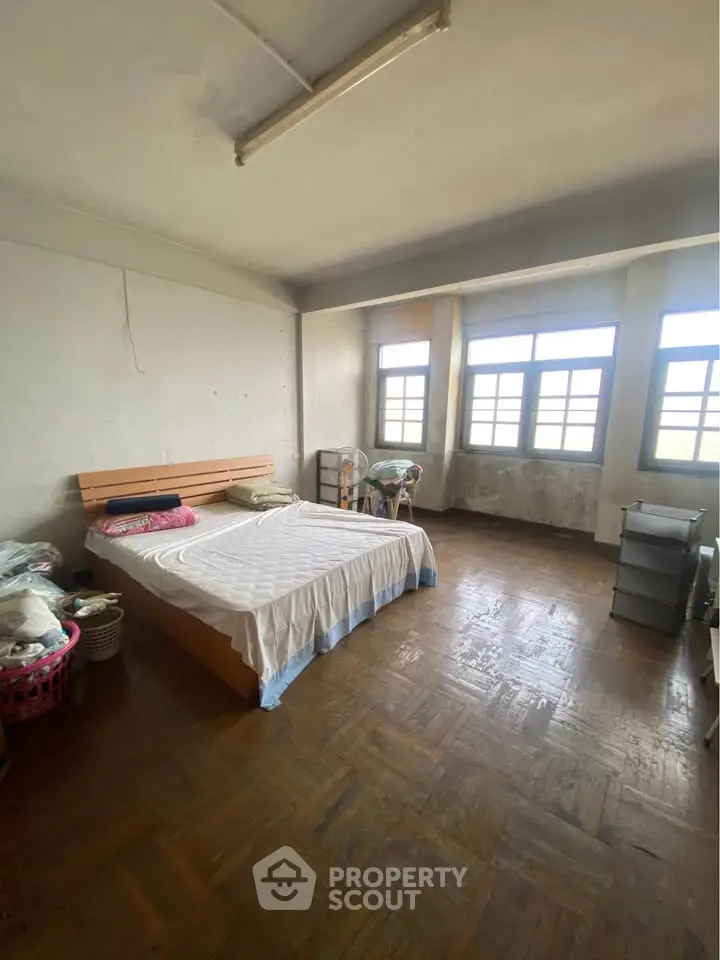 Spacious bedroom with large windows and wooden flooring, ideal for natural light lovers.