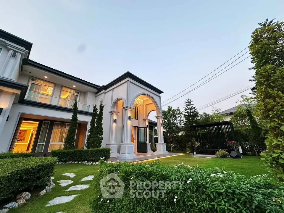 Luxurious two-story home with elegant columns and lush garden in a serene neighborhood.