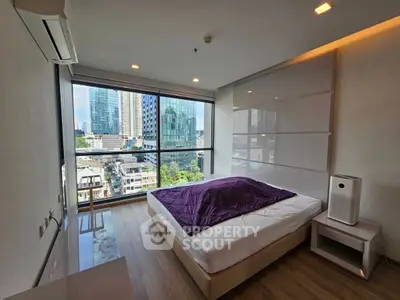 Modern bedroom with city view, featuring large windows and stylish decor.