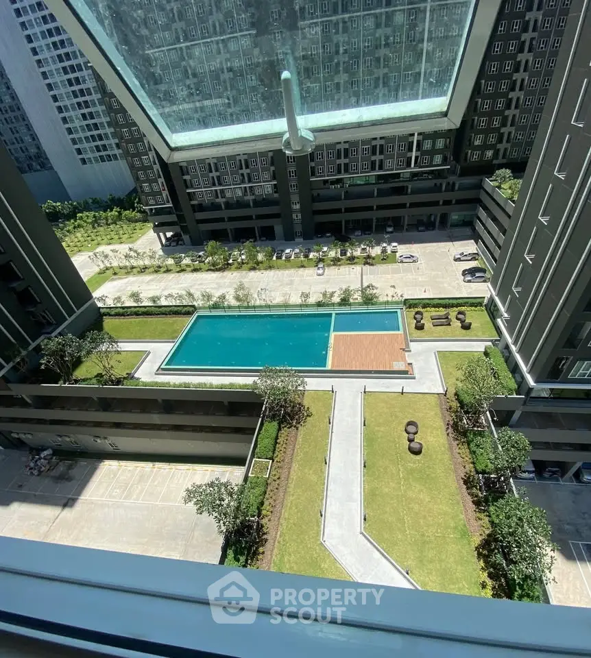Stunning aerial view of modern apartment complex with pool and landscaped garden, perfect for urban living.