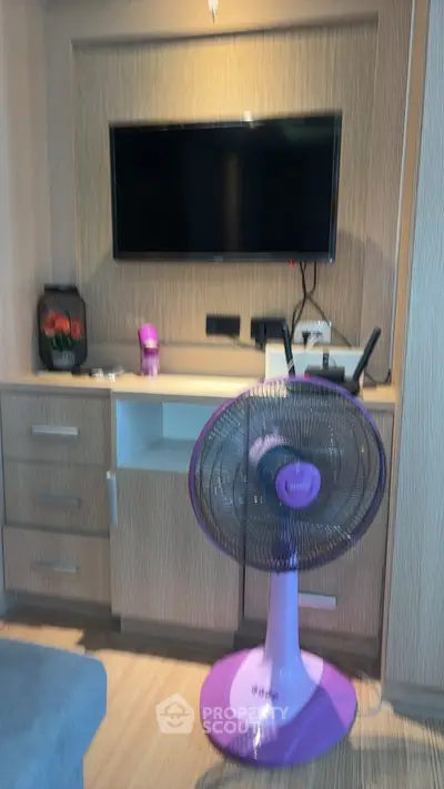 Modern living room with TV and stylish purple fan, perfect for relaxation.