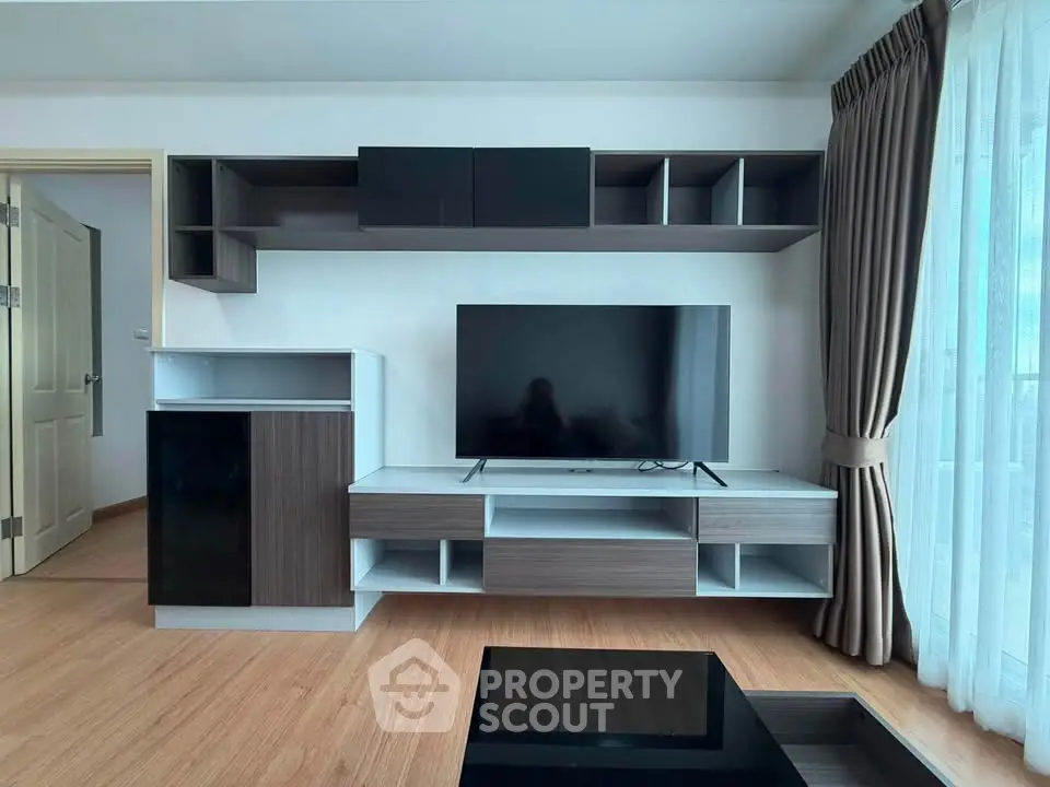 Modern living room with sleek TV unit and large window for natural light.