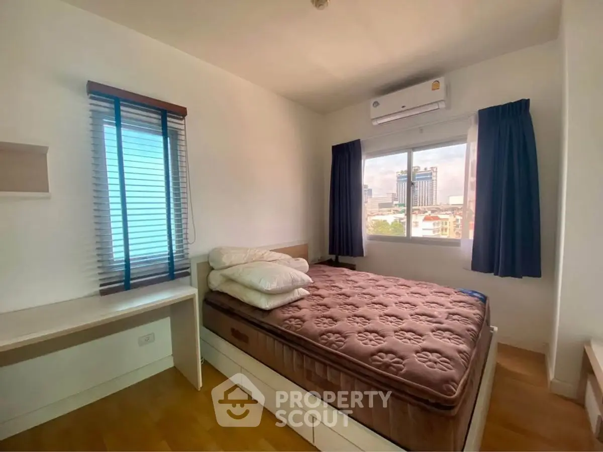 Cozy bedroom with city view, featuring a comfortable bed and ample natural light.
