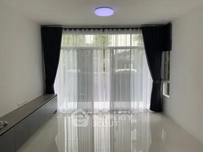 Spacious living room with large windows and modern curtains, perfect for natural light.