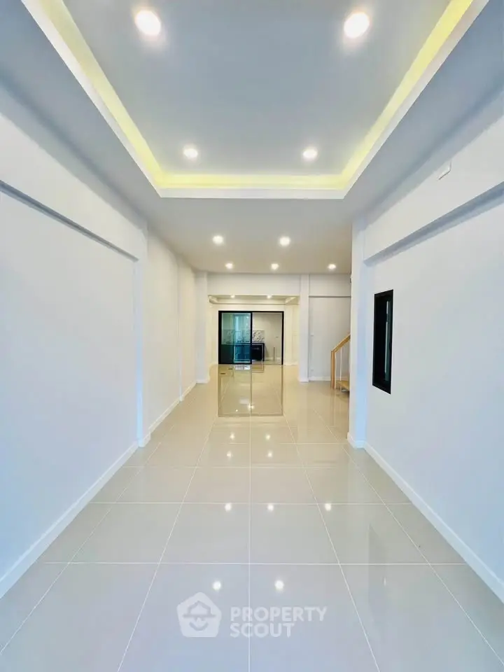 Spacious modern interior with glossy tiled floors and recessed lighting, perfect for versatile living or office space.