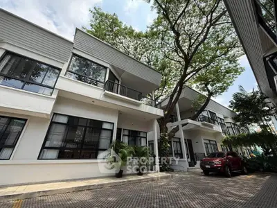 Modern townhouse exterior with lush greenery and parked car in a serene neighborhood.