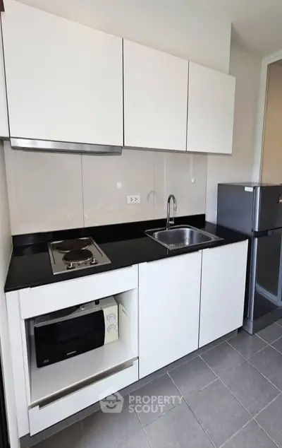 Modern kitchen with sleek white cabinets and compact appliances in a stylish apartment.