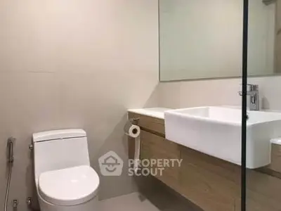 Modern bathroom with sleek fixtures and minimalist design, featuring a large mirror and elegant sink.