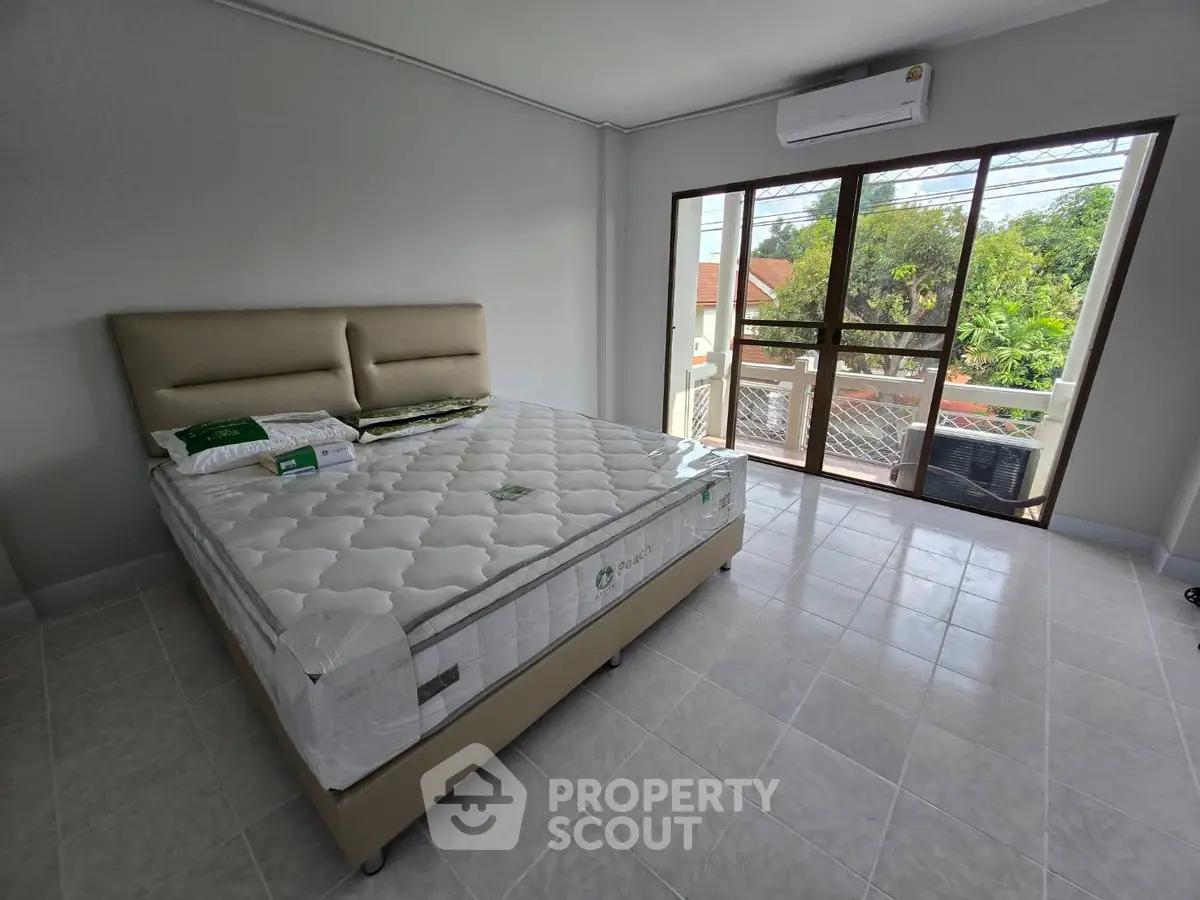 Spacious bedroom with large window and balcony access, featuring a comfortable bed and air conditioning.