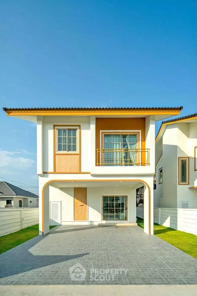 Modern two-story house with balcony and spacious driveway in sunny neighborhood.
