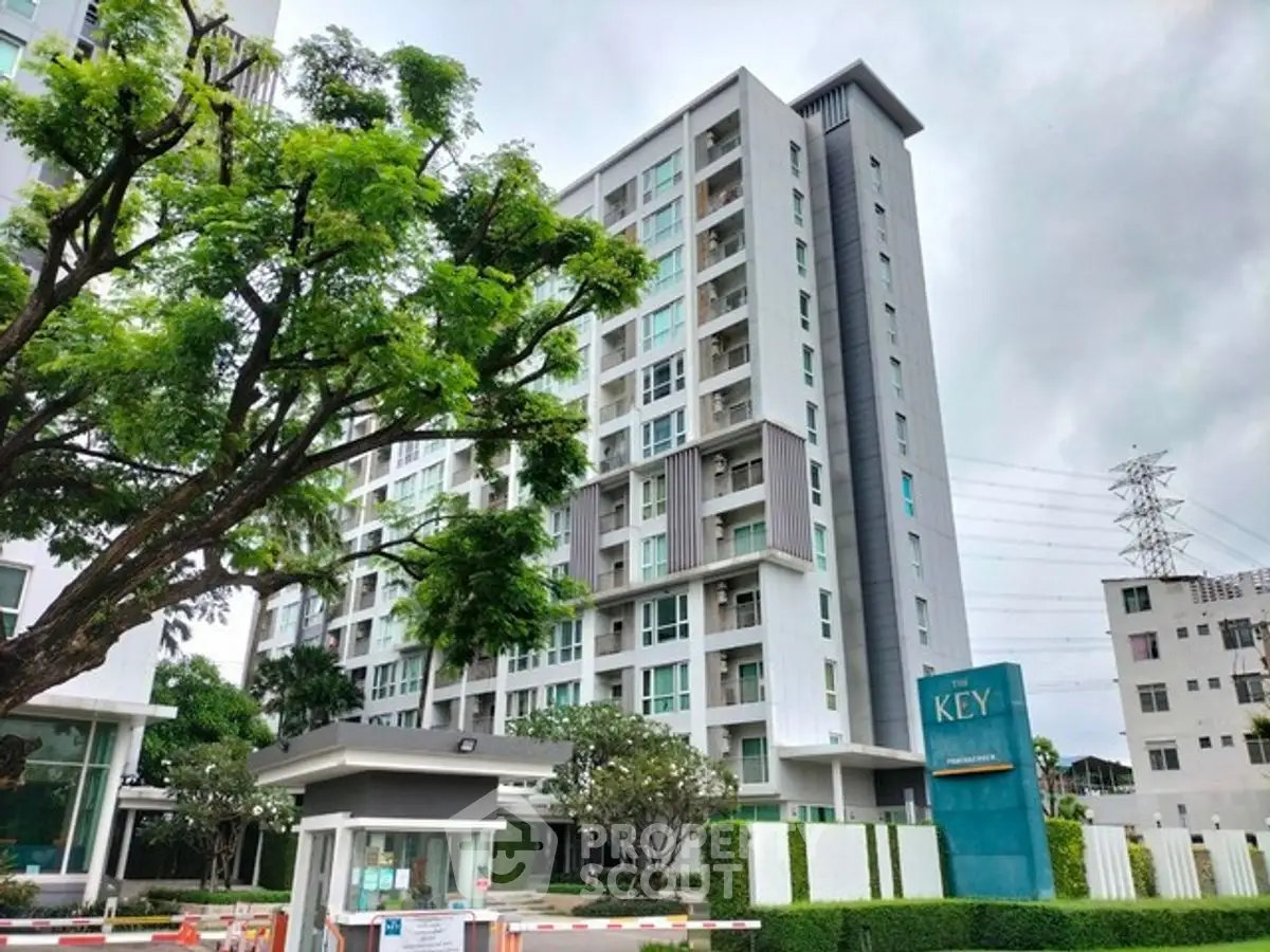 Modern condominium building with lush greenery and secure entrance in urban setting.