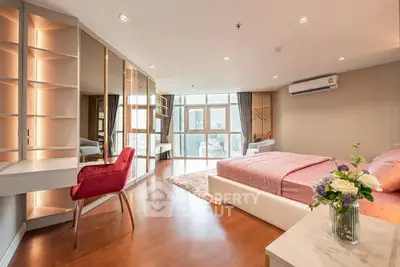 Luxurious bedroom with city view, elegant decor, and modern furnishings in high-rise apartment.