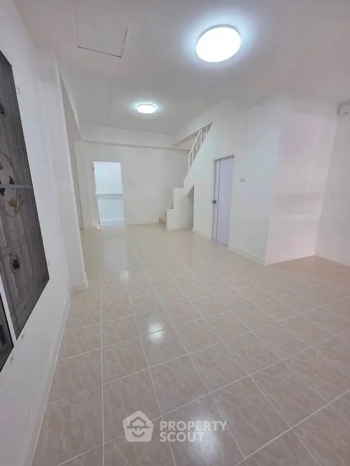 Spacious tiled living area with staircase and bright lighting, ideal for modern family living.