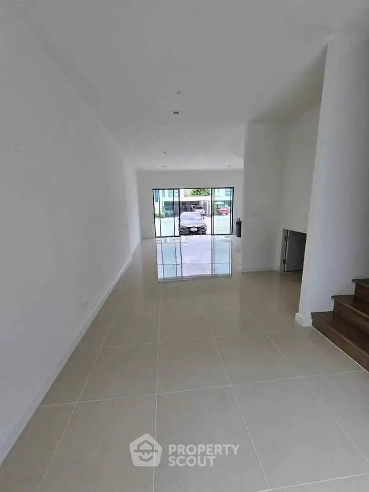 Spacious modern living room with large windows and glossy tile flooring.