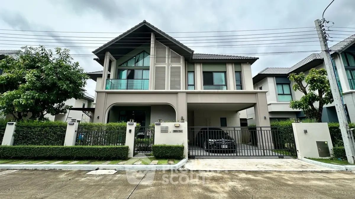 Modern two-story house with sleek design, large windows, and a gated driveway in a suburban neighborhood.