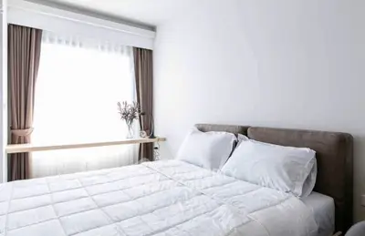 Bright and cozy bedroom with large window and elegant curtains, perfect for relaxation.
