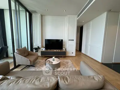 Modern living room with sleek furniture and large TV, featuring elegant decor and natural light.