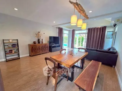 Spacious living room with wooden furniture and large windows overlooking garden.