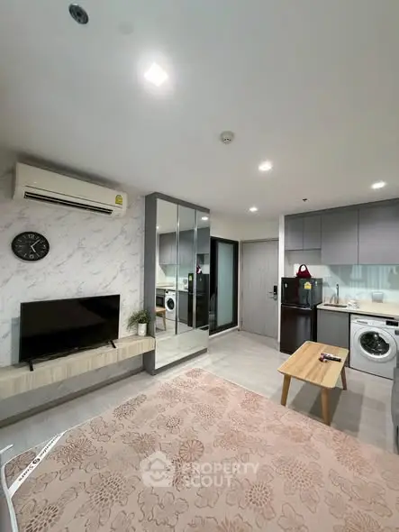 Modern living room with open kitchen, featuring sleek appliances and stylish decor in a cozy apartment.