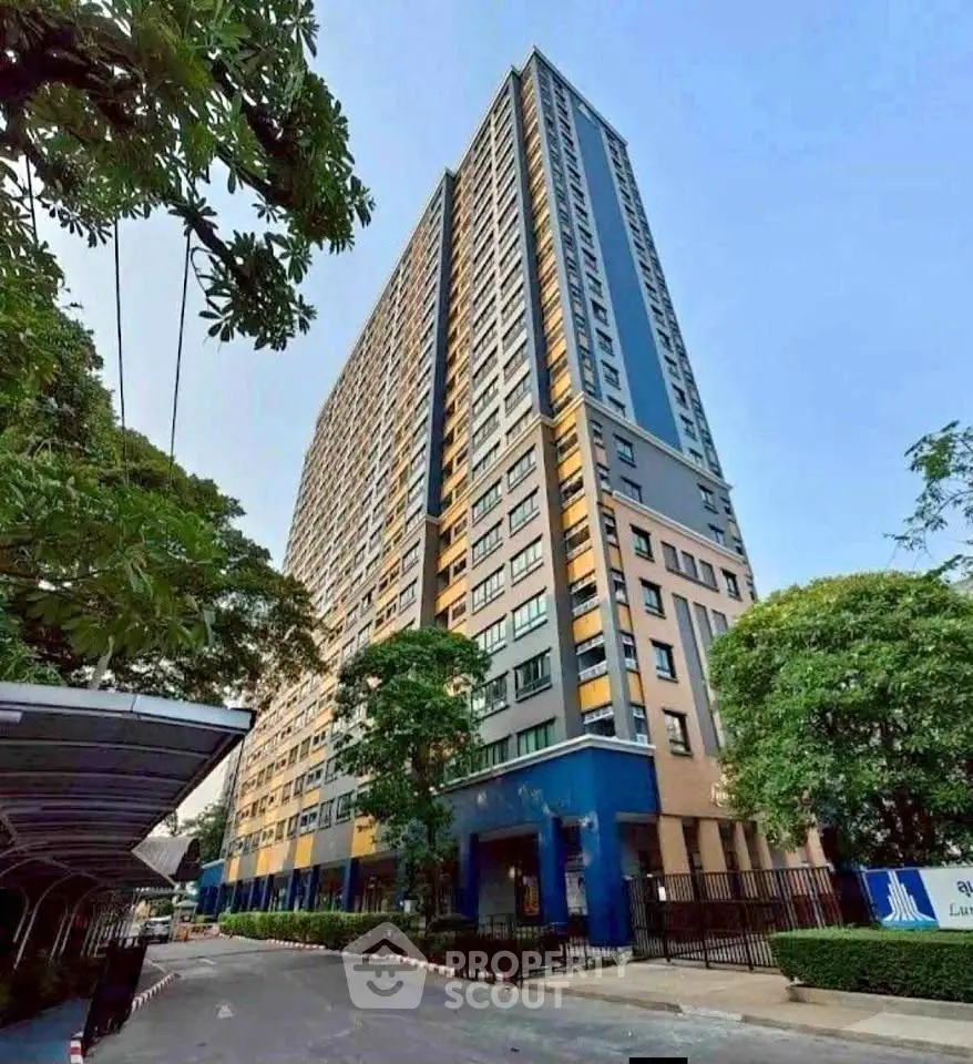 Modern high-rise residential building with lush greenery and clear blue sky.