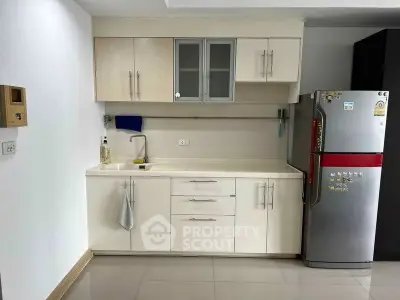 Modern kitchen with sleek cabinetry and stainless steel fridge in a stylish apartment.