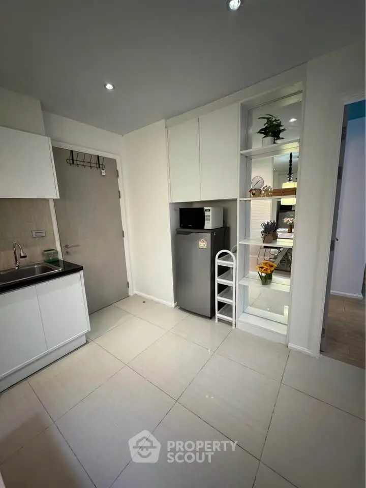 Modern kitchen with sleek white cabinets and stainless steel fridge in a bright apartment.