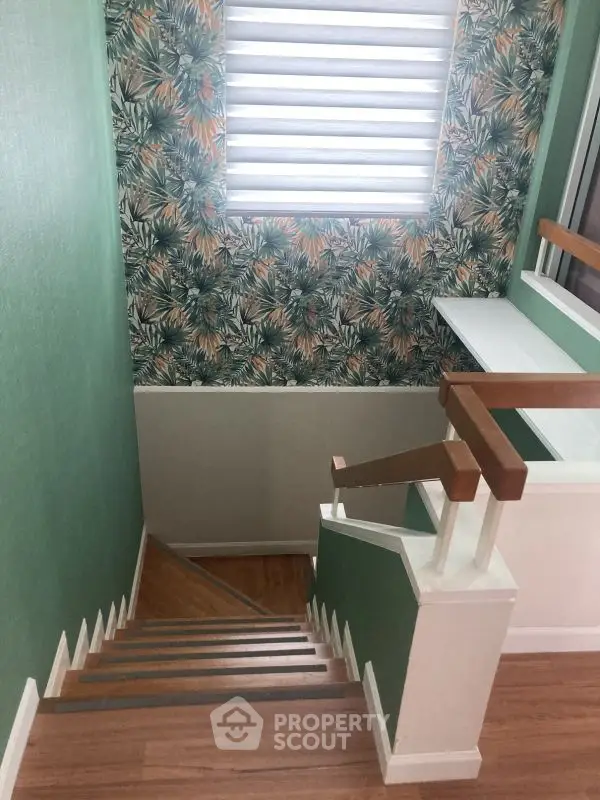 Stylish staircase with tropical wallpaper and wooden handrails in modern home