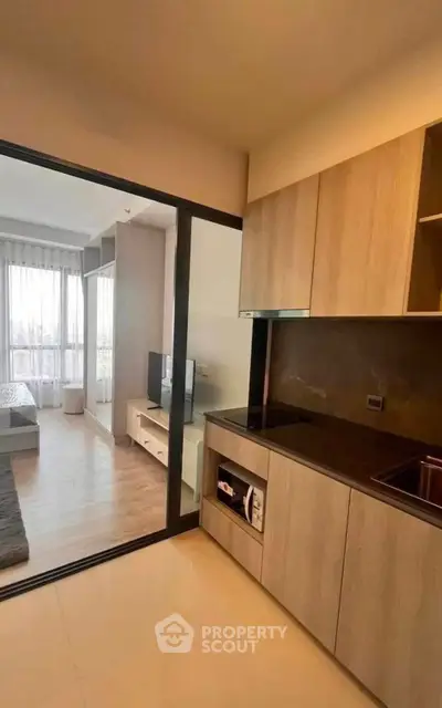 Modern apartment with open kitchen and cozy living area, featuring sleek cabinetry and natural light.