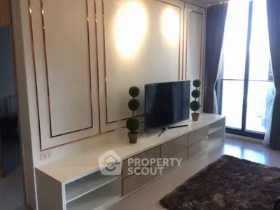 Modern living room with sleek TV stand and large window offering natural light.