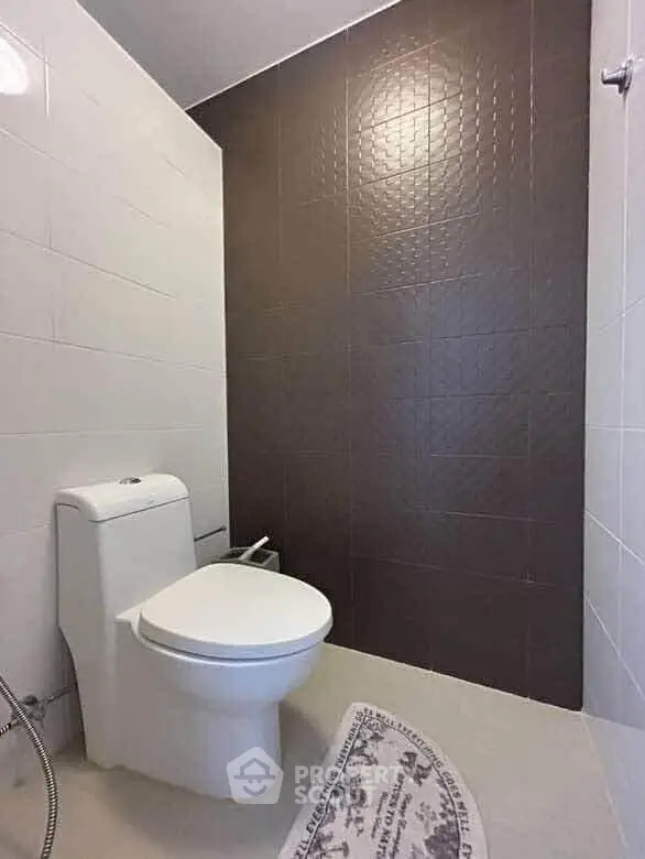 Modern bathroom with sleek design and neutral tiles, featuring a contemporary toilet.