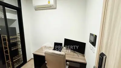 Modern study room with desk, chair, and computer setup in a sleek apartment.