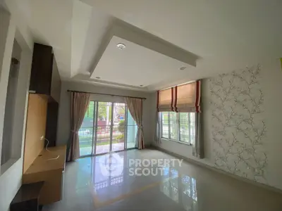 Spacious living room with large windows and elegant ceiling design, offering a bright and airy atmosphere.