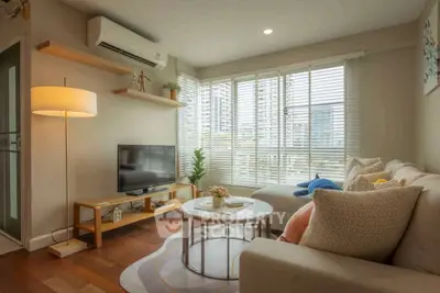 Cozy living room with modern decor, large windows, and comfortable seating in a stylish apartment.